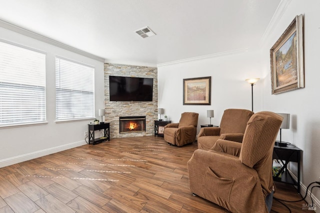 living area with a fireplace, crown molding, visible vents, wood finished floors, and baseboards