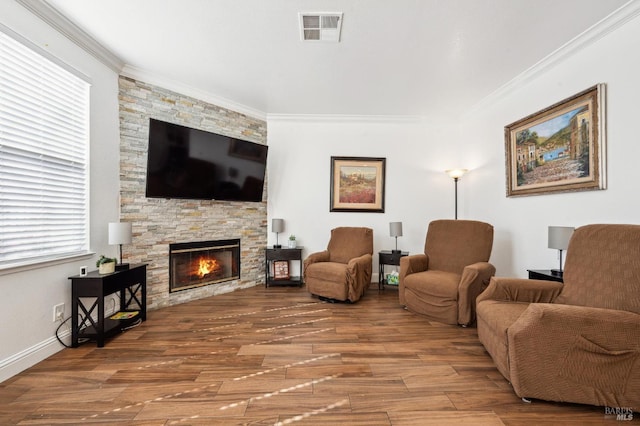 living room with a fireplace, wood finished floors, visible vents, baseboards, and ornamental molding