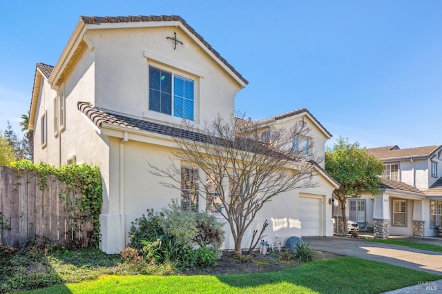 mediterranean / spanish-style house with a tile roof, stucco siding, fence, a garage, and driveway