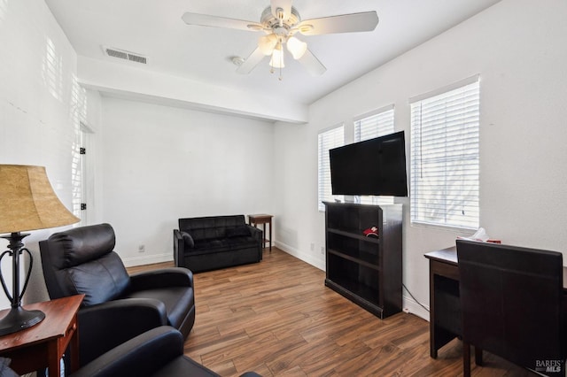 living area featuring a ceiling fan, baseboards, visible vents, and wood finished floors