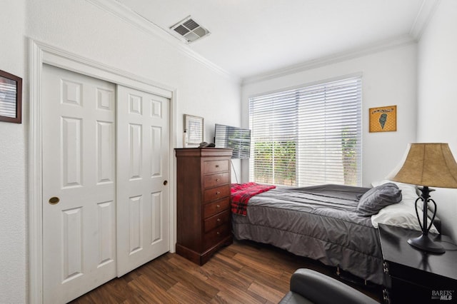 bedroom featuring a closet, visible vents, dark wood-type flooring, and ornamental molding