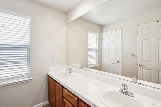 bathroom featuring a sink, baseboards, and double vanity