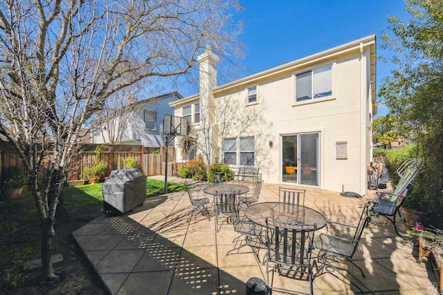 rear view of property featuring outdoor dining area, a patio area, fence, and stucco siding