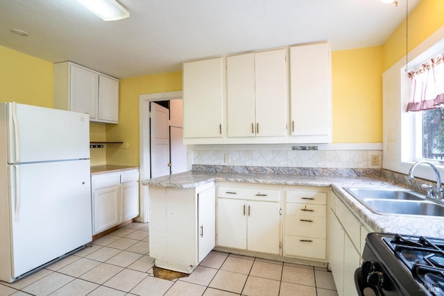 kitchen featuring a sink, light countertops, freestanding refrigerator, and gas stove