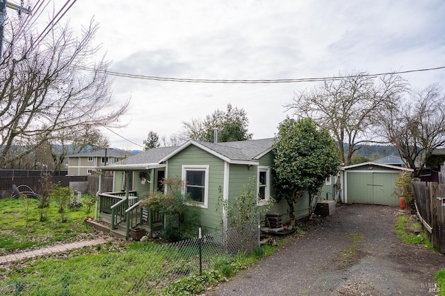 view of front of home with an outbuilding, driveway, a fenced backyard, a storage shed, and a garage