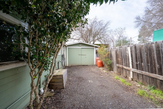 exterior space with driveway, a garage, fence, a storage unit, and an outdoor structure