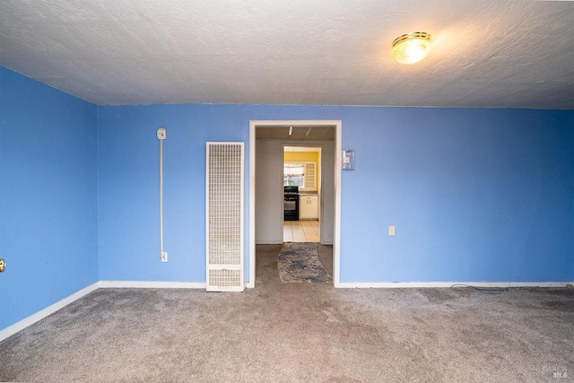 carpeted empty room featuring a textured ceiling, a heating unit, and baseboards