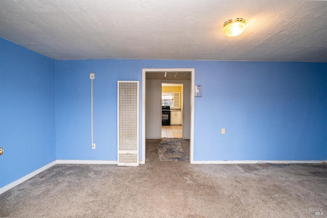 carpeted spare room with a textured ceiling, a heating unit, and baseboards