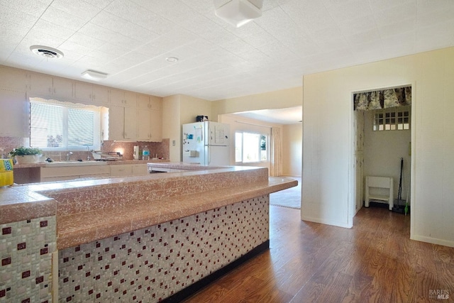 kitchen with tile countertops, visible vents, backsplash, freestanding refrigerator, and wood finished floors