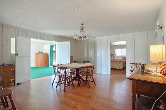 dining area with wood finished floors and an inviting chandelier