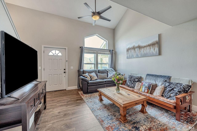 living area with a ceiling fan, light wood-type flooring, high vaulted ceiling, and baseboards