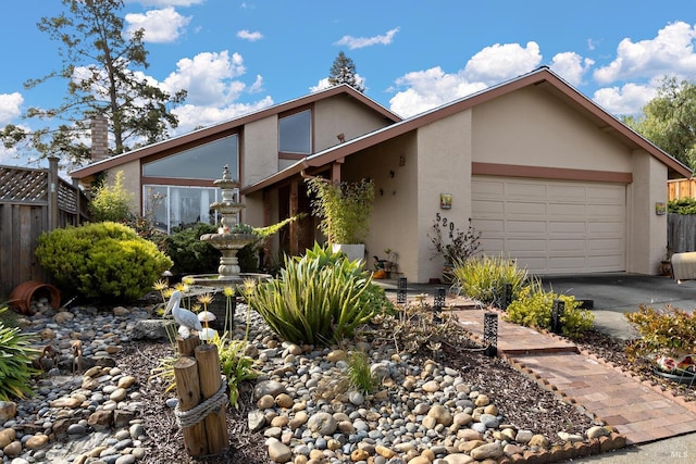 mid-century inspired home featuring fence, an attached garage, and stucco siding