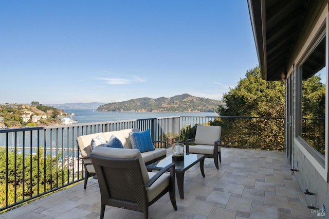 balcony with an outdoor hangout area and a water and mountain view