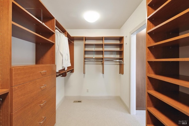 walk in closet with visible vents and light carpet