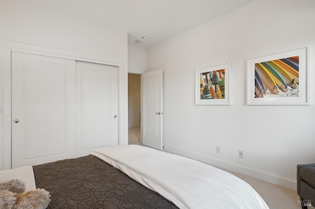 carpeted bedroom with a closet and baseboards