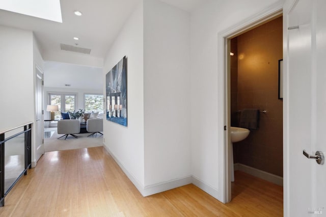 hall featuring a skylight, recessed lighting, visible vents, light wood-style flooring, and baseboards