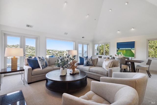 living area with high vaulted ceiling, visible vents, and light carpet