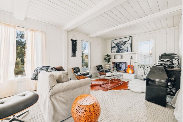 living room with a brick fireplace, beam ceiling, and wood finished floors