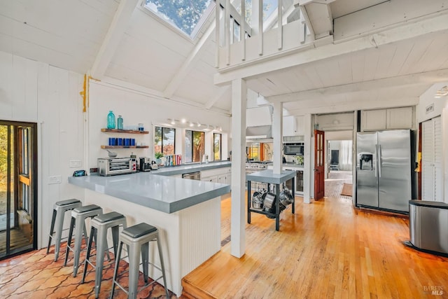 kitchen with a peninsula, a healthy amount of sunlight, a breakfast bar area, and stainless steel appliances