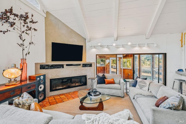 living room with vaulted ceiling with beams and a glass covered fireplace