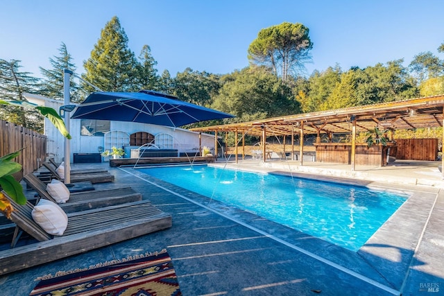 view of pool with an outdoor bar, fence, a fenced in pool, and a patio