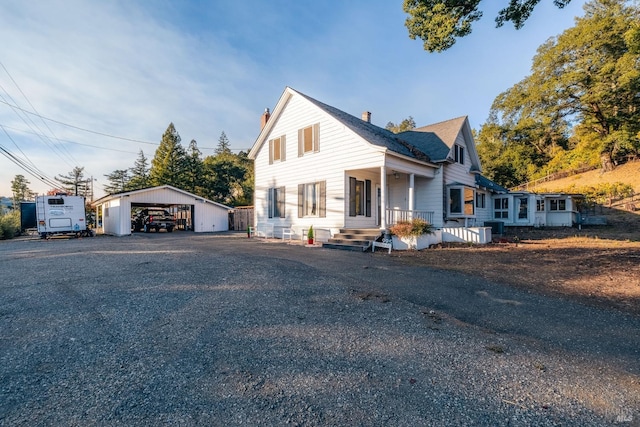 view of front of house with roof with shingles, a chimney, a carport, and an outbuilding