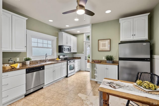 kitchen with dark stone countertops, white cabinetry, appliances with stainless steel finishes, and a sink