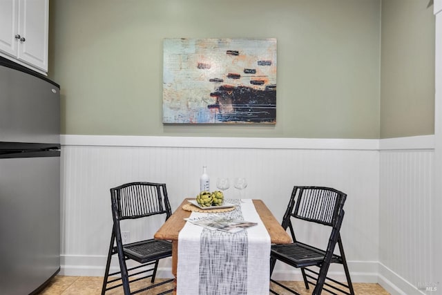 dining room featuring a wainscoted wall and light tile patterned floors