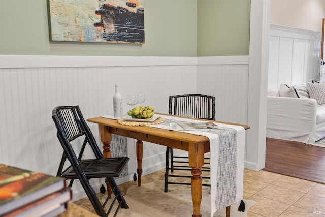 dining room featuring a wainscoted wall and light tile patterned flooring