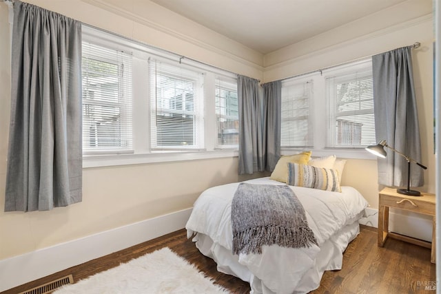 bedroom with baseboards, visible vents, and dark wood-type flooring