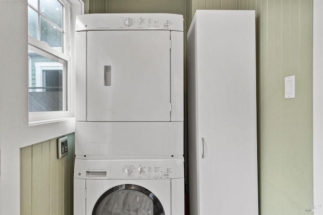 clothes washing area featuring stacked washer and dryer and laundry area