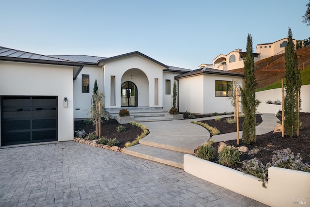 view of front of property with metal roof, a garage, decorative driveway, stucco siding, and a standing seam roof