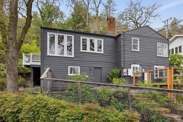 back of house featuring a chimney and a wooden deck