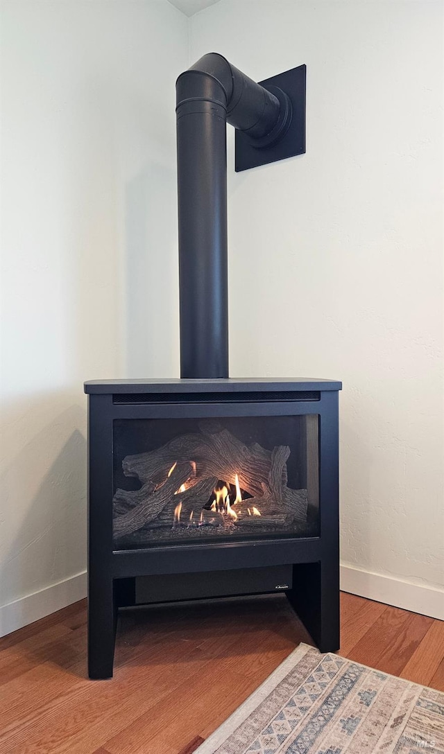 room details featuring a wood stove, baseboards, and wood finished floors