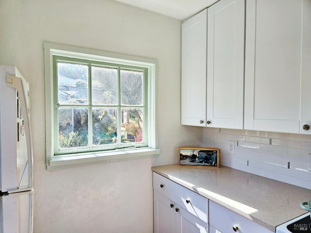 195 Ocean View Ave, Bodega Bay, CA 94923 - kitchen with backsplash, white cabinetry, light countertops, and freestanding refrigerator