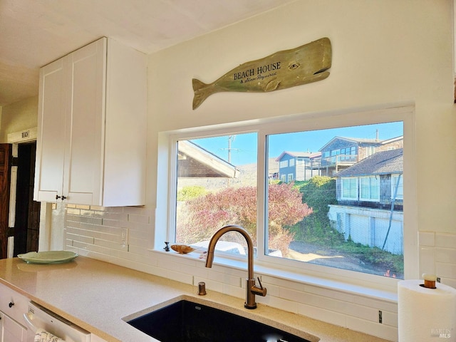 kitchen featuring light countertops, white cabinetry, a sink, and stainless steel dishwasher