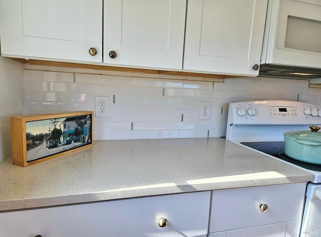 kitchen with white appliances, white cabinets, backsplash, and light stone countertops