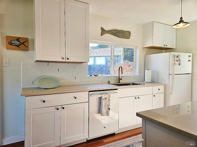 kitchen with white appliances, white cabinets, hanging light fixtures, and a sink