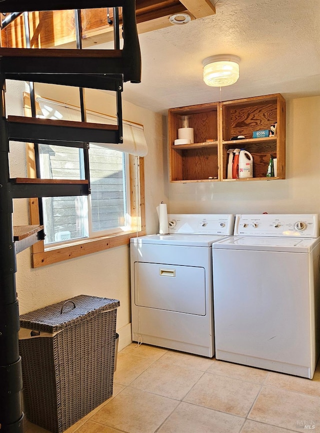 laundry area with laundry area, washer and clothes dryer, a textured ceiling, and light tile patterned floors