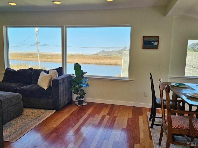 living room with recessed lighting, a water view, wood finished floors, and baseboards