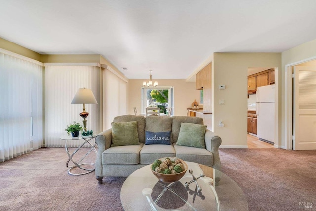 living room with a chandelier, light carpet, and baseboards