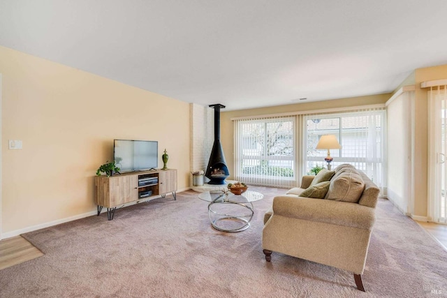 living area with a wood stove, baseboards, and light colored carpet