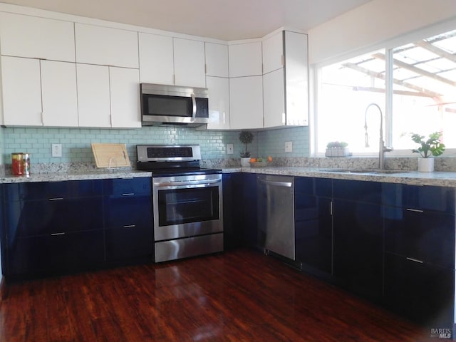 kitchen featuring stainless steel appliances, white cabinetry, a sink, and modern cabinets