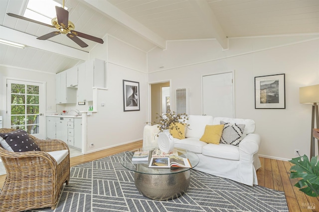 living area with lofted ceiling with beams, ceiling fan, baseboards, and wood finished floors