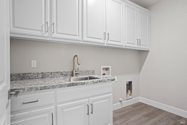 clothes washing area featuring hookup for a washing machine, baseboards, light wood finished floors, cabinet space, and a sink