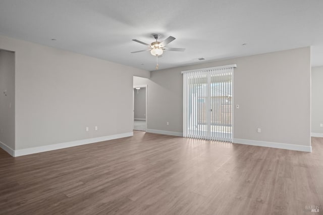 spare room featuring visible vents, baseboards, wood finished floors, and a ceiling fan