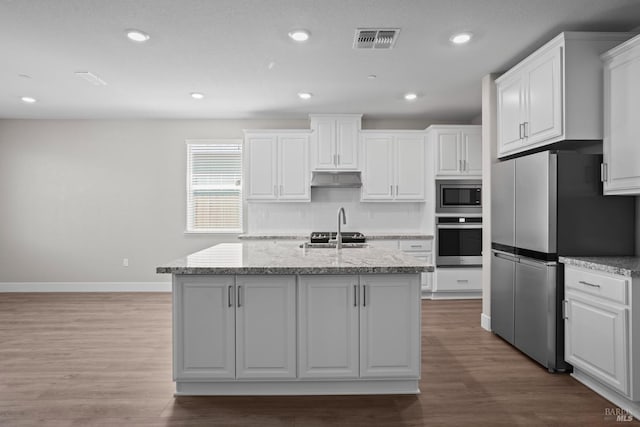 kitchen with visible vents, backsplash, stainless steel appliances, wood finished floors, and white cabinetry