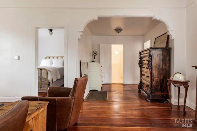 foyer with dark wood-style floors, arched walkways, and baseboards