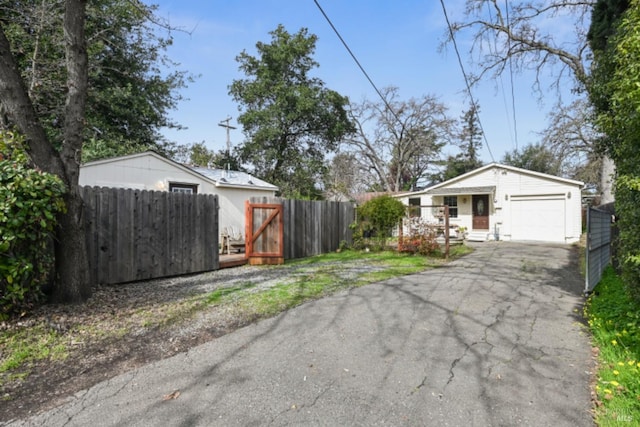 exterior space featuring an attached garage, fence, and aphalt driveway