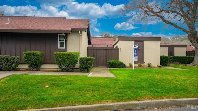 view of home's exterior with stucco siding, a yard, and fence